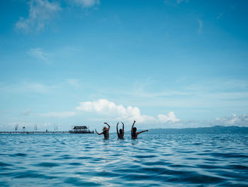 People swimming in sea against blue sky