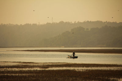 Man on boat in lake against sky