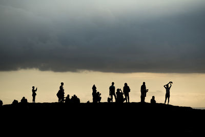 Silhouette people photographing on landscape against sky