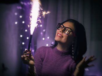 Smiling young woman with illuminated firework at night