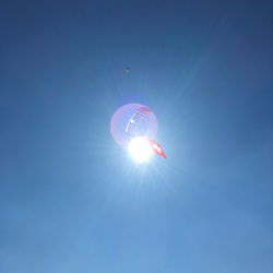Low angle view of sun against clear blue sky