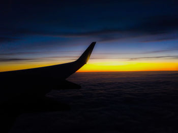 Airplane flying over sea against sky during sunset