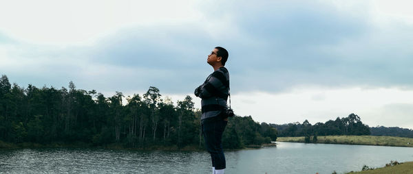 Side view of man looking away while standing by lake