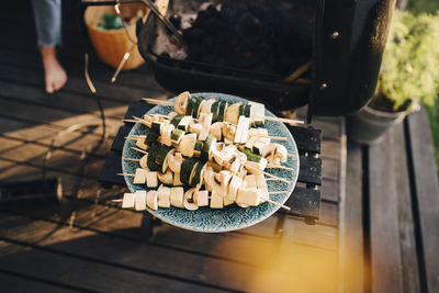 High angle close-up of chopped mushroom and zucchini in plate by barbecue grill