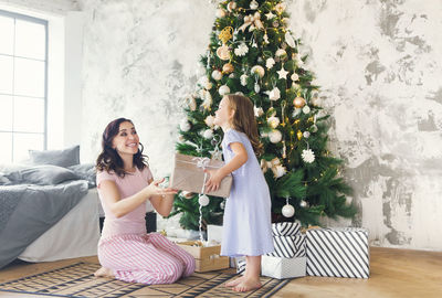 Mother giving christmas present to daughter at home