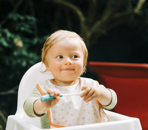 Cute baby holding toy while sitting outdoors