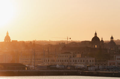 Buildings in city against sky during sunset