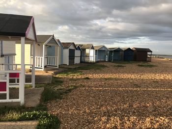 Houses on field by buildings against sky