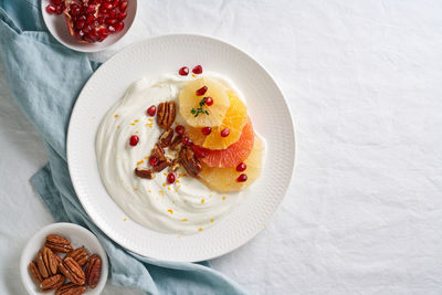 Ricotta with citrus fruits, pecans and honey on white plate on white table. sweet and healthy 