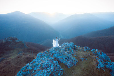 Rear view of bride standing on mountain against sky