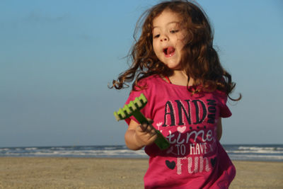 Girl standing on beach against clear sky