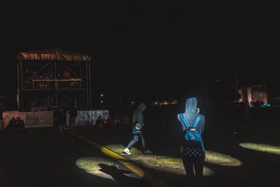 People standing in illuminated city against sky at night