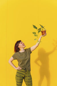 Woman standing against yellow wall