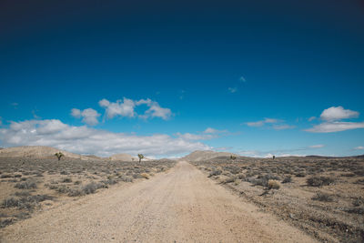 Road amidst landscape against blue sky