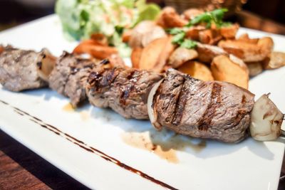 Barbecued beef skewered on plate with vegetables