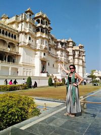 Portrait of smiling mature woman gesturing towards palace