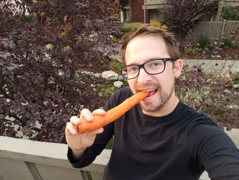 Portrait of man eating carrot outdoors
