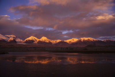 Scenic view of lake by mountains against sky during sunset