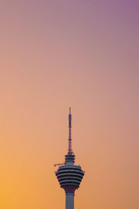 Communications tower in city against sky during sunset