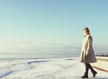 Woman walking on beach against sky