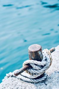 High angle view of rope tied on metal over sea