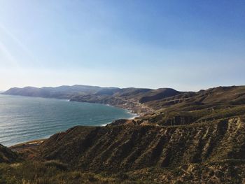 Scenic view of sea and mountains against clear sky
