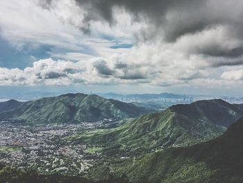 Scenic view of green mountains against cloudy sky