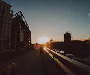 Railroad tracks amidst buildings in city against sky during sunset