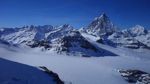 Scenic view of snowcapped mountains against clear blue sky