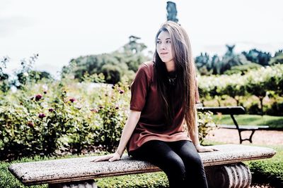 Young woman looking away while sitting on seat at park