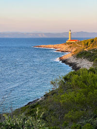 Lighthouse by sea against sky