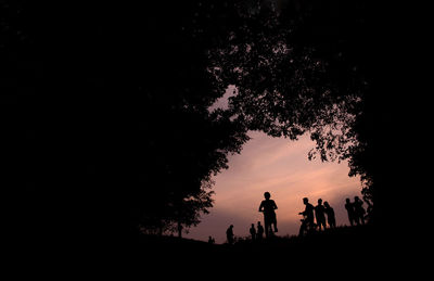 Silhouette people by tree against sky during sunset