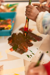 Cropped hand of woman painting on table