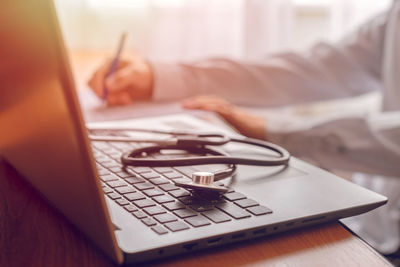 Close-up of man using laptop on table