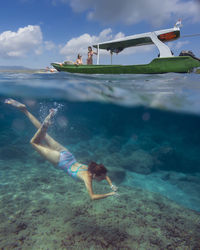 Young woman snorkeling near the boat in ocean, underwater view