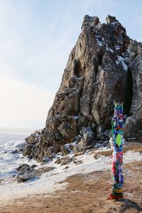Man standing on rock by sea against sky