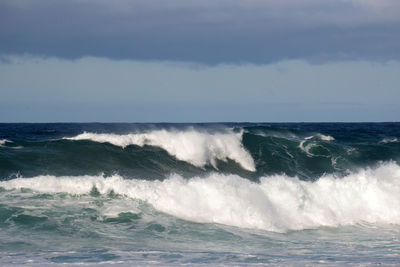 Waves flowing at sea against sky