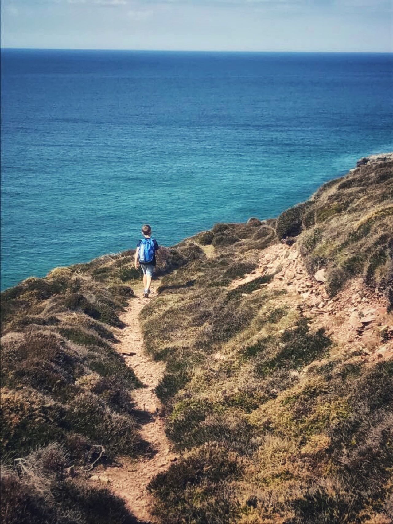 A boy walking along the coastal path way ahead of anyone else