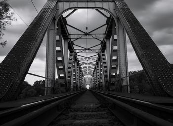 Bridge over railroad tracks against sky