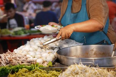 Midsection of woman preparing food at market stall