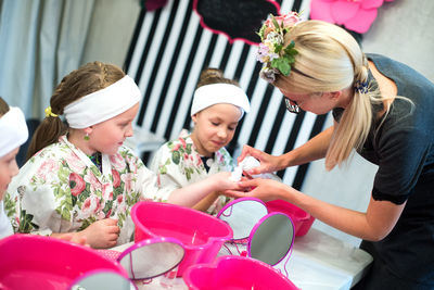 Beautician applying cream on children hands at spa