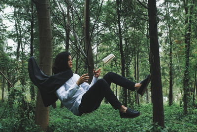 Man with book levitating in forest