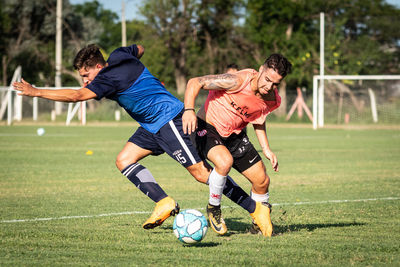 Low section of men playing soccer on field