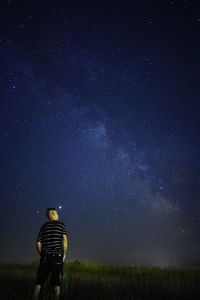 Rear view of man on field against sky at night