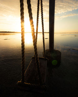 Wooden posts on beach against sky during sunset