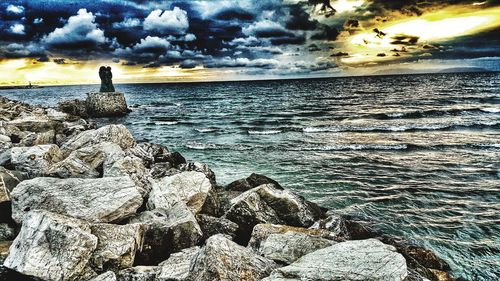 Man looking at sea against sky during sunset