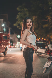 Portrait of smiling woman standing on street in city