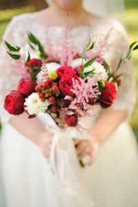 Midsection of bride holding bouquet