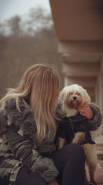 Portrait of woman with dog sitting outdoors