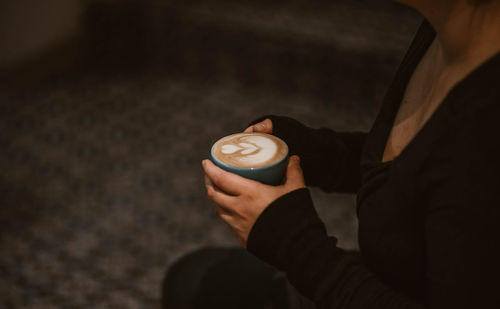 Midsection of woman holding coffee cup at night